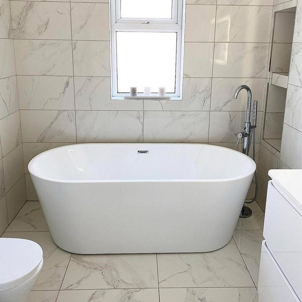 white bathtub against white marble tiles