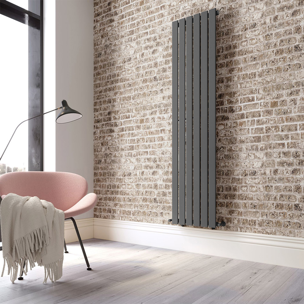 Tall grey radiator against a brick wall