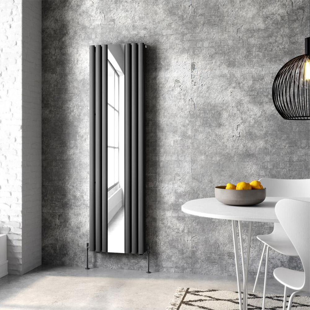 tall grey radiator with a mirror against a grey brick wall