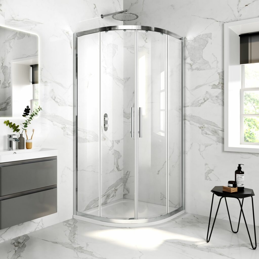 Chrome and glass quadrant shower enclosure in the corner of a marble tiled bathroom