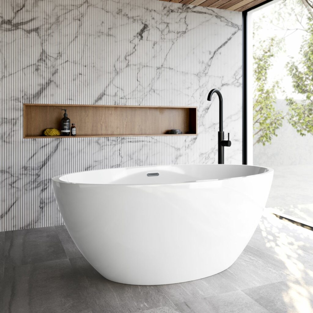 Large freestanding acrylic white oval shaped bath in an open plan bathroom with marble tiled walls