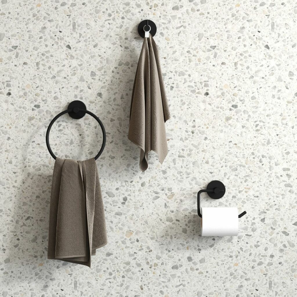 three black bathroom accessories hanging on a beige terrazzo wall